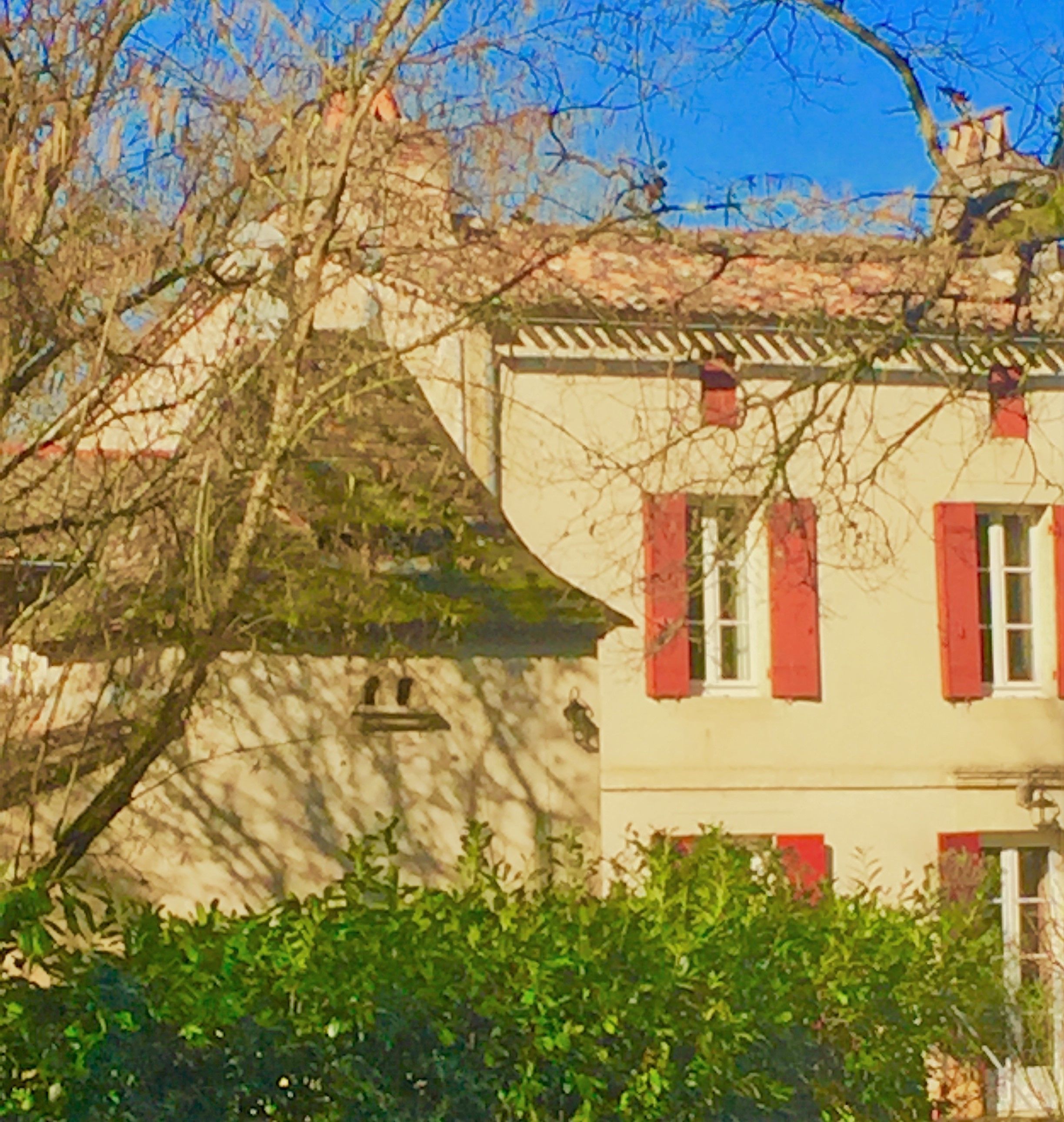 Un bâtiment doté d’un toit en pente, de volets rouges et d’un mur en pierre.