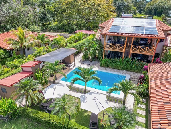Un resort con piscina, zonas de estar cubiertas y paneles solares.