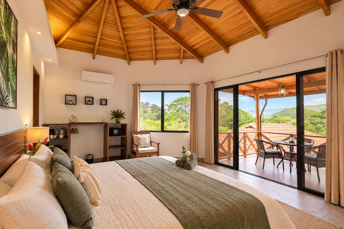 Un dormitorio con una cama grande, un escritorio y vistas al exterior.