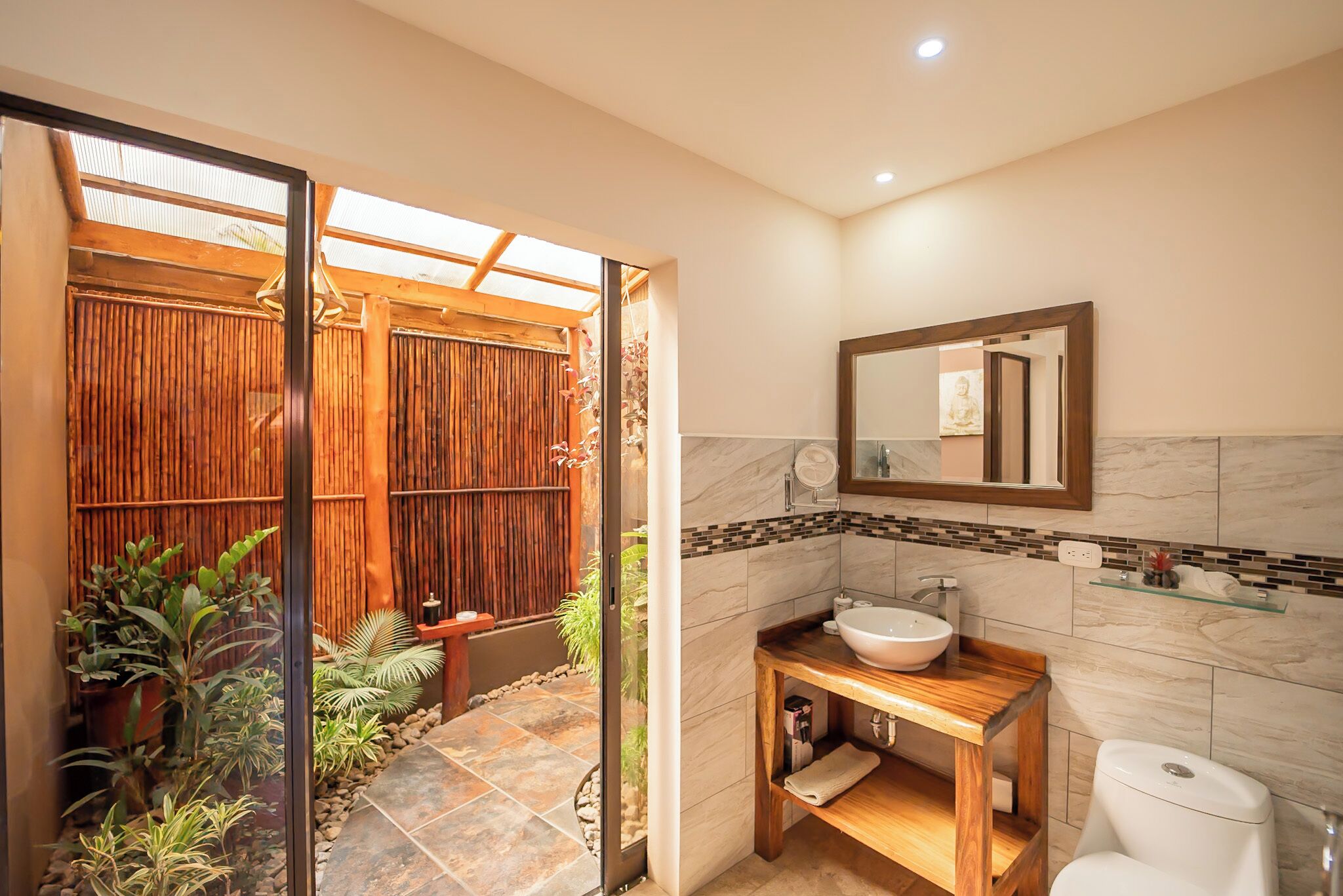 A bathroom with a wooden vanity, a large mirror, and a toilet.