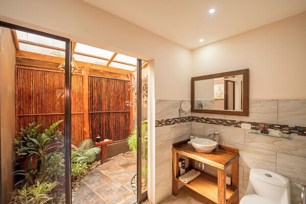 A bathroom with a wooden vanity, a large mirror, and a toilet.