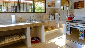 Una cocina con un lavamanos, estufa y diversos utensilios.