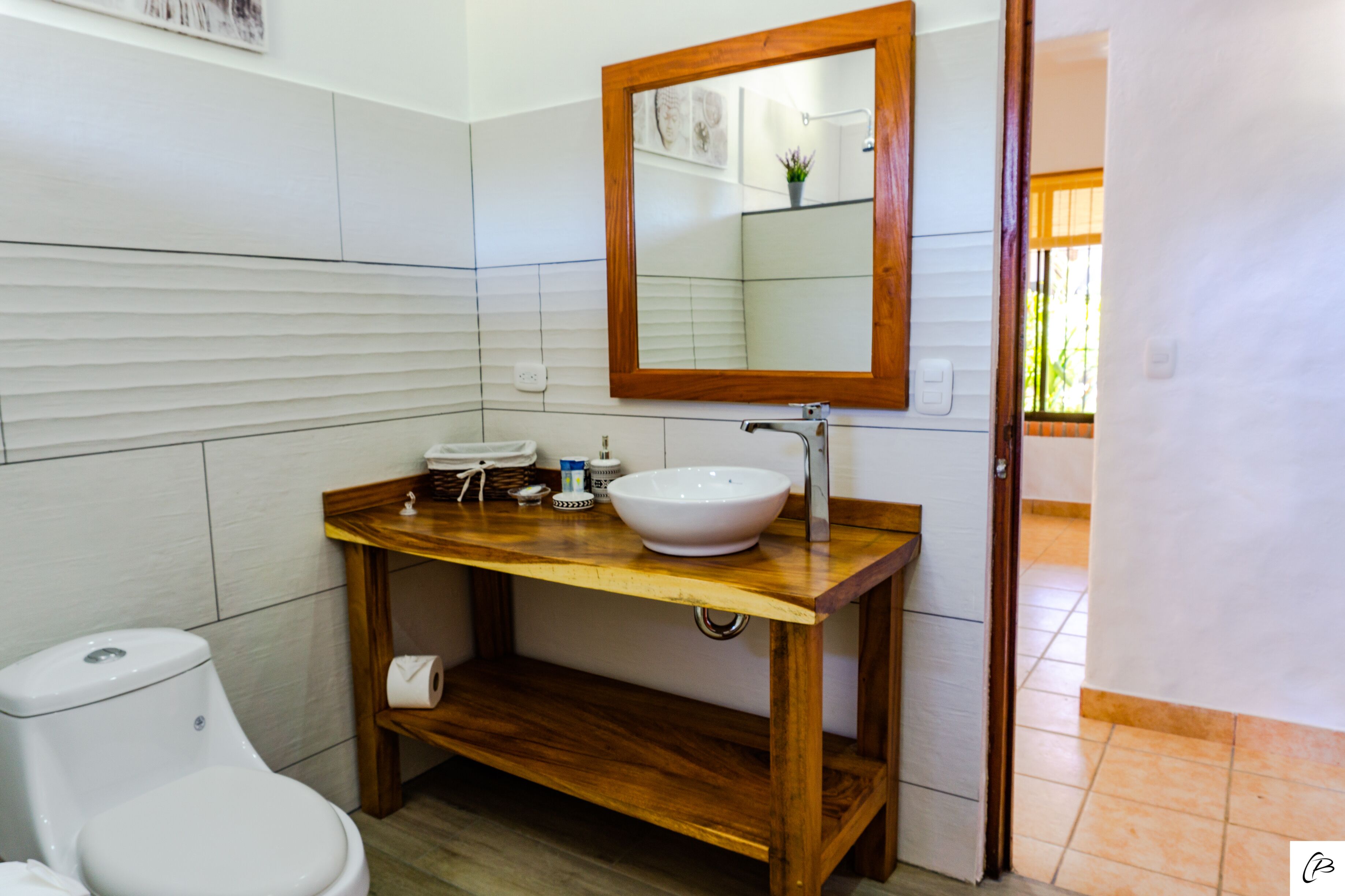 A bathroom with a wooden vanity, white sink, and toilet.