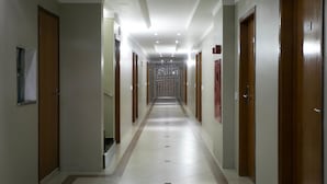 Um corredor comprido e estreito com portas de madeira em ambos os lados, que leva a um chão de azulejos.