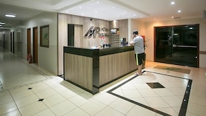 Bancada de recepção de hotel com acabamento em madeira e tela digital.