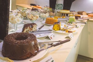A buffet table with various desserts and a chocolate-covered donut. - Hotel Paranoá Jaboticabal (Jaboticabal)