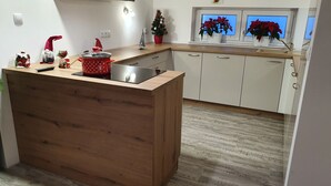 Eine Küche mit einer Holzeinsel, weißen Schränken und einem kleinen Weihnachtsbaum.