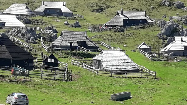 Ein ländliches Dorf mit traditionellen Steinhaus, einem eingezäunten Bereich und einem Auto.