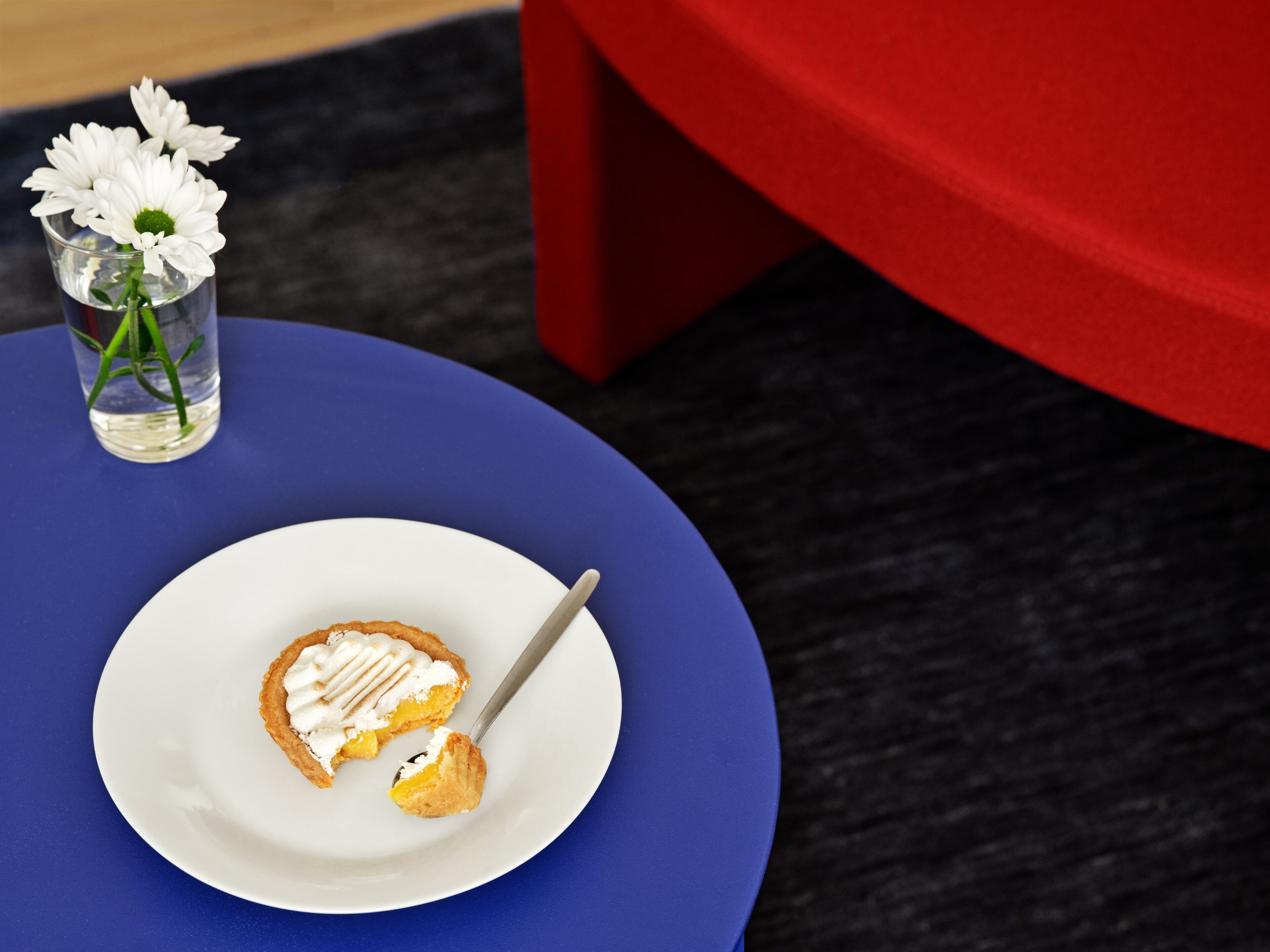 A plate with a slice of pie and a spoon on a blue table.