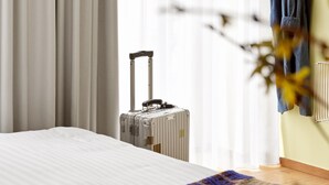 A hotel room with a bed, a suitcase, and a window with curtains. - BRIK Apartment Hotel (Copenhagen)
