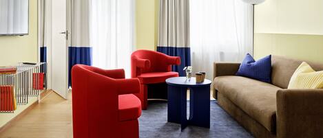 Uma sala de estar moderna com uma poltrona vermelha, uma mesa lateral azul e um sofá marrom.