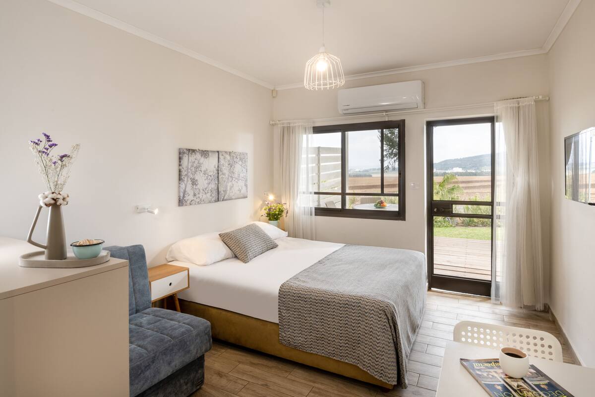 Ein Schlafzimmer mit Bett, Nachttisch und Schreibtisch mit Stuhl. Ein Fenster bietet Blick ins Freie.