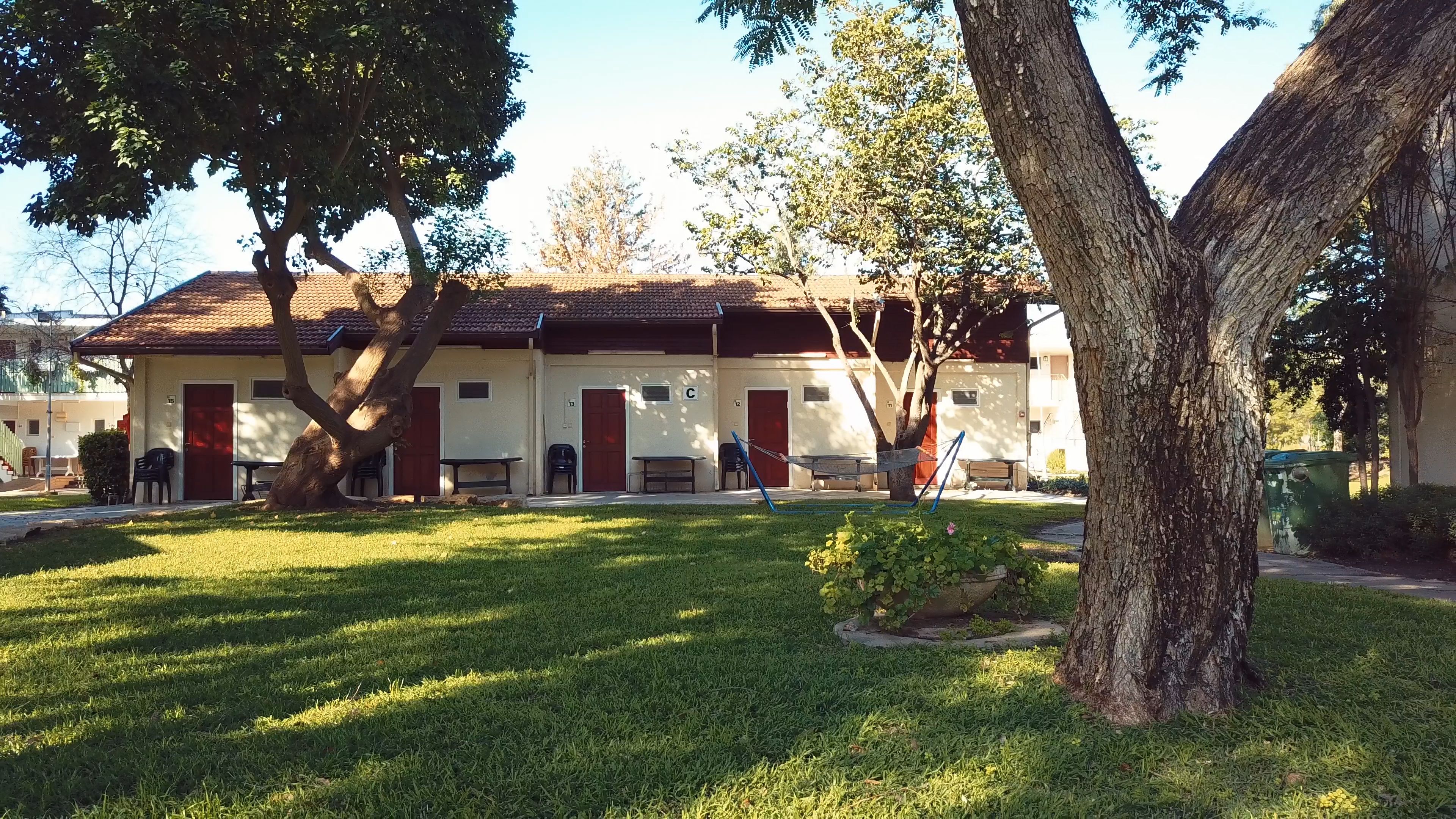 A building with a tiled roof, multiple doors, and a grassy lawn.