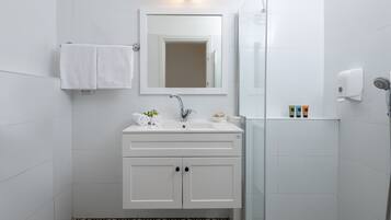 Un baño moderno con un tocador blanco, un espejo, una ducha y un piso con diseño.