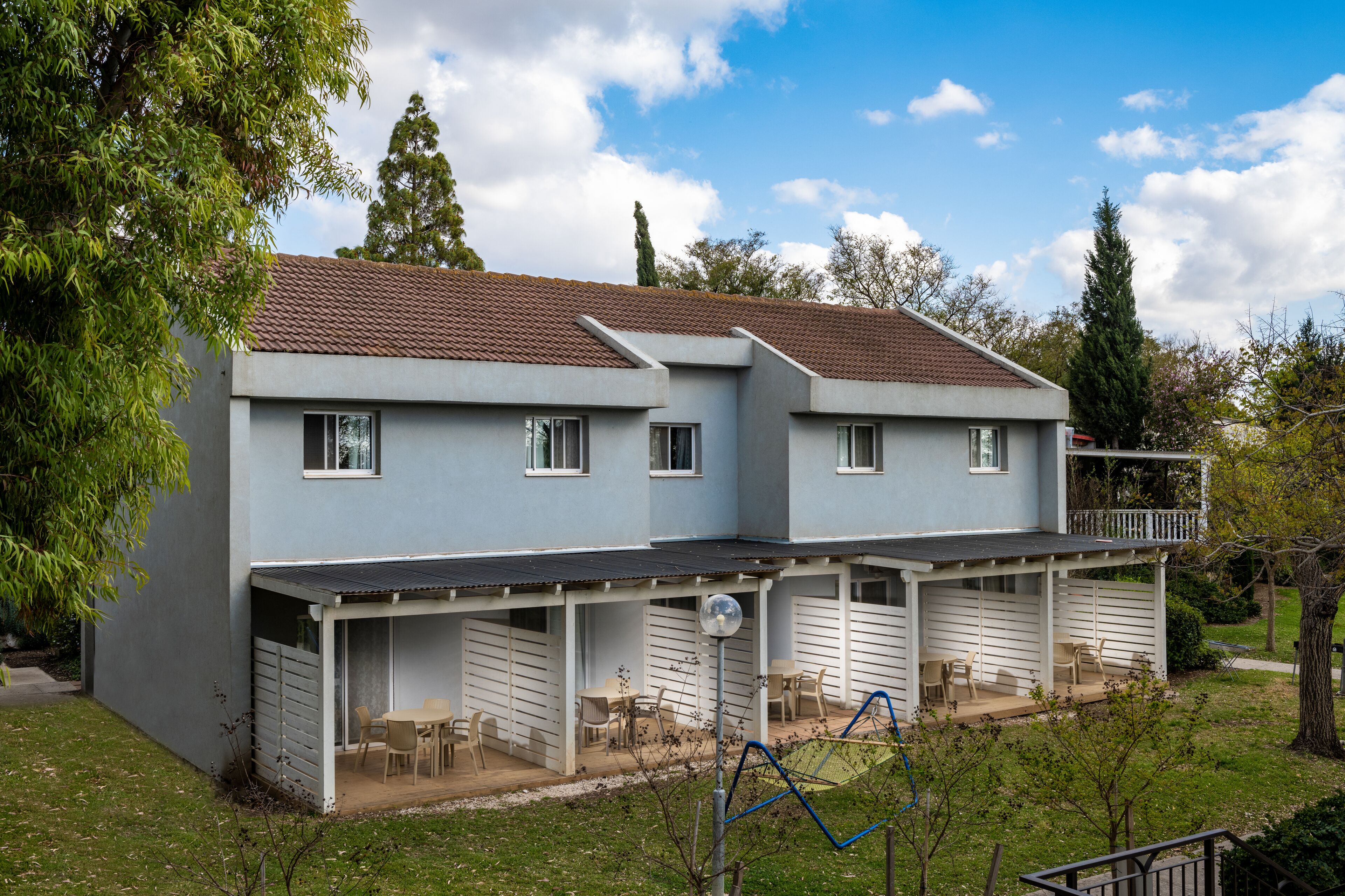A two-story house with a covered patio area, multiple windows, and a fenced yard.