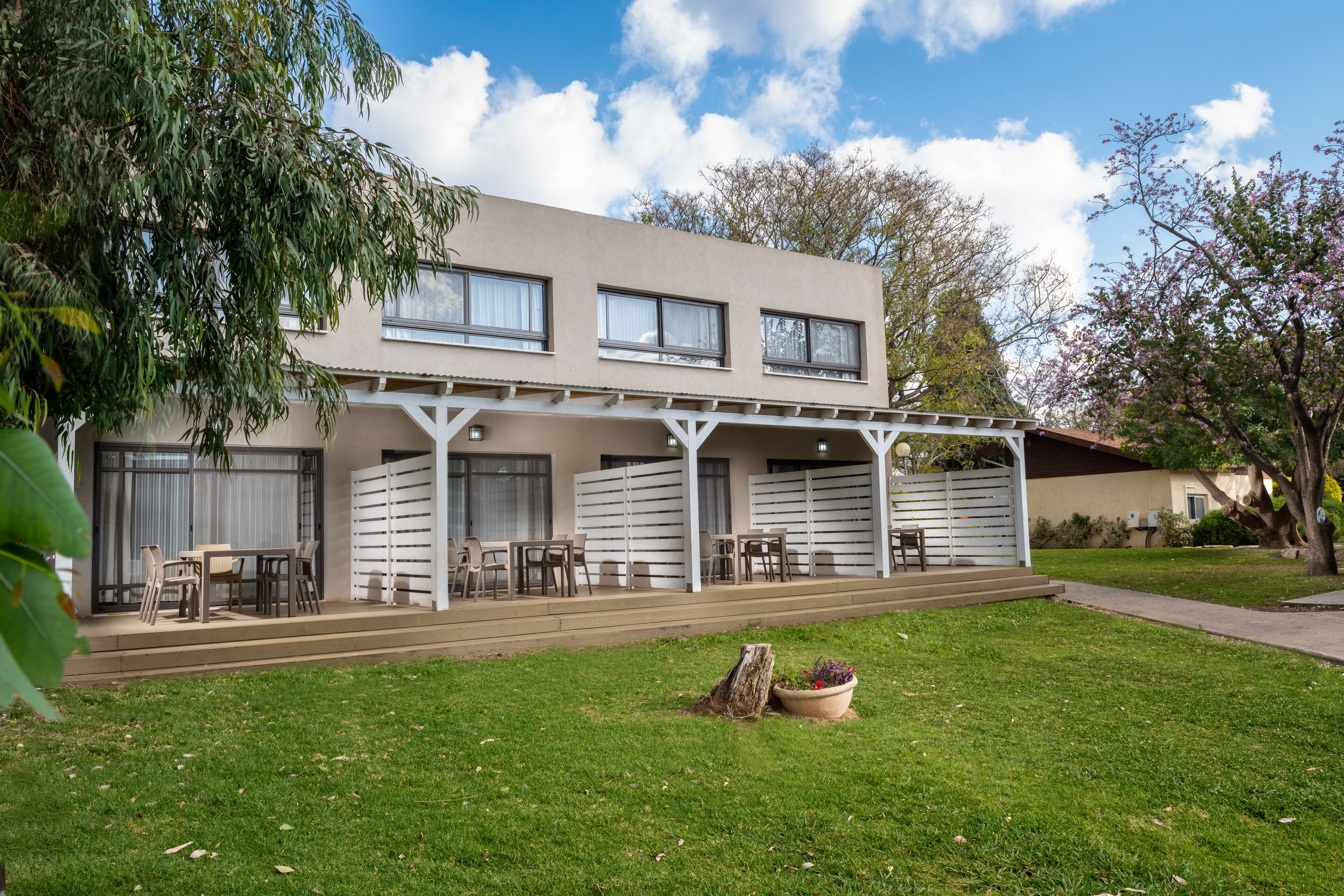 A two-story building with a covered patio area, outdoor seating, and a well-maintained lawn.