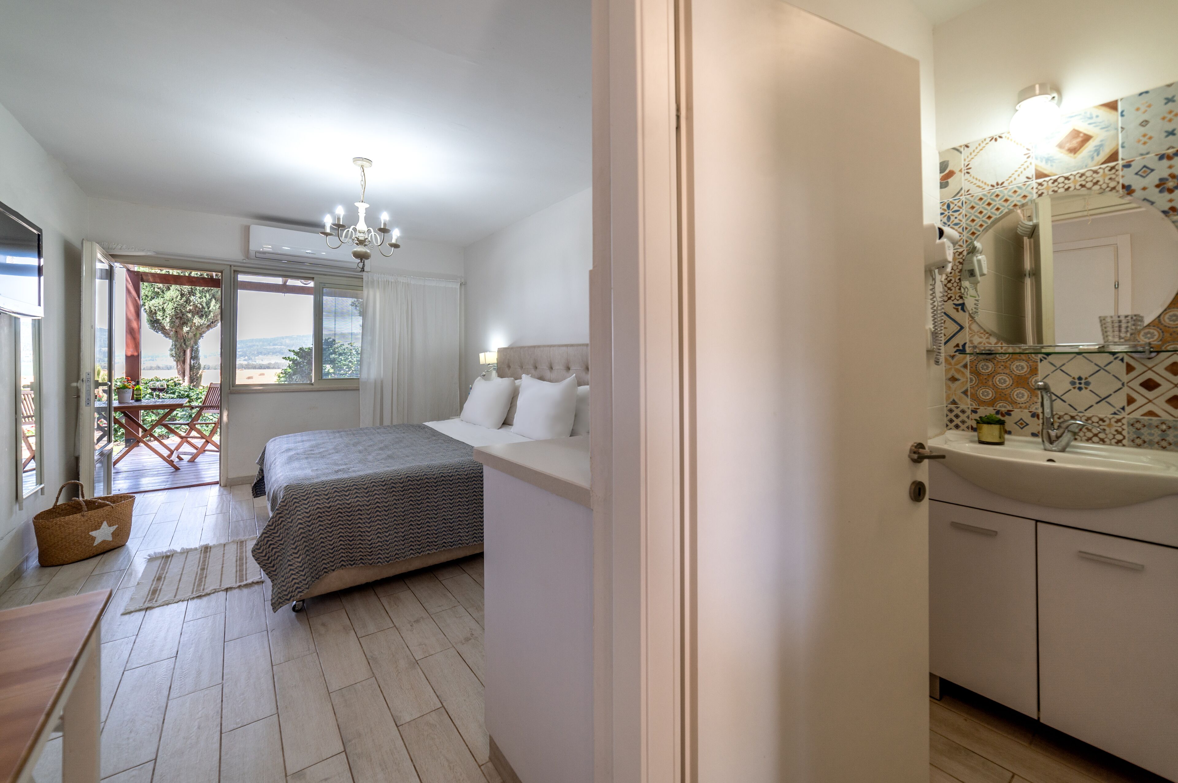 A bedroom with a bed, a window, and a bathroom with a sink and mirror.