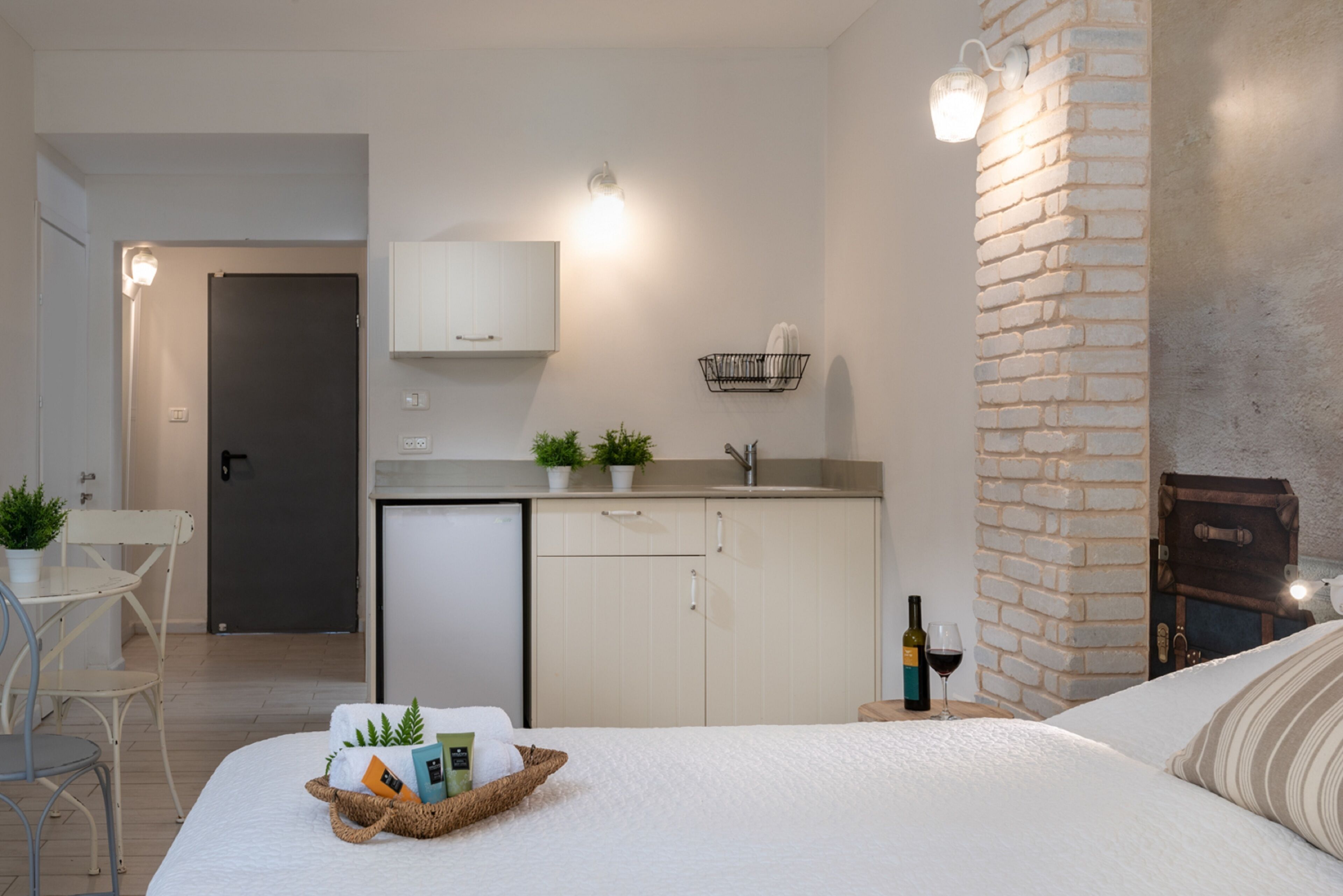 Una habitación de hotel moderna con cama, mesita de noche y una pequeña kitchenette.