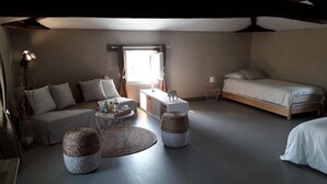 Ein modernes Schlafzimmer mit einer Couch, einem Bett, einem kleinen Tisch und zwei gewebten Körben.