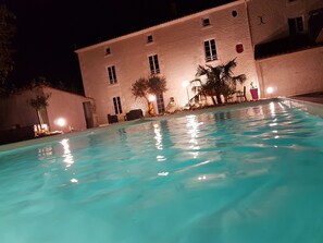 A swimming pool with a white building in the background. - Chambres d'Hôtes Le Marais Picotin (Saint-Pierre-le-Vieux)