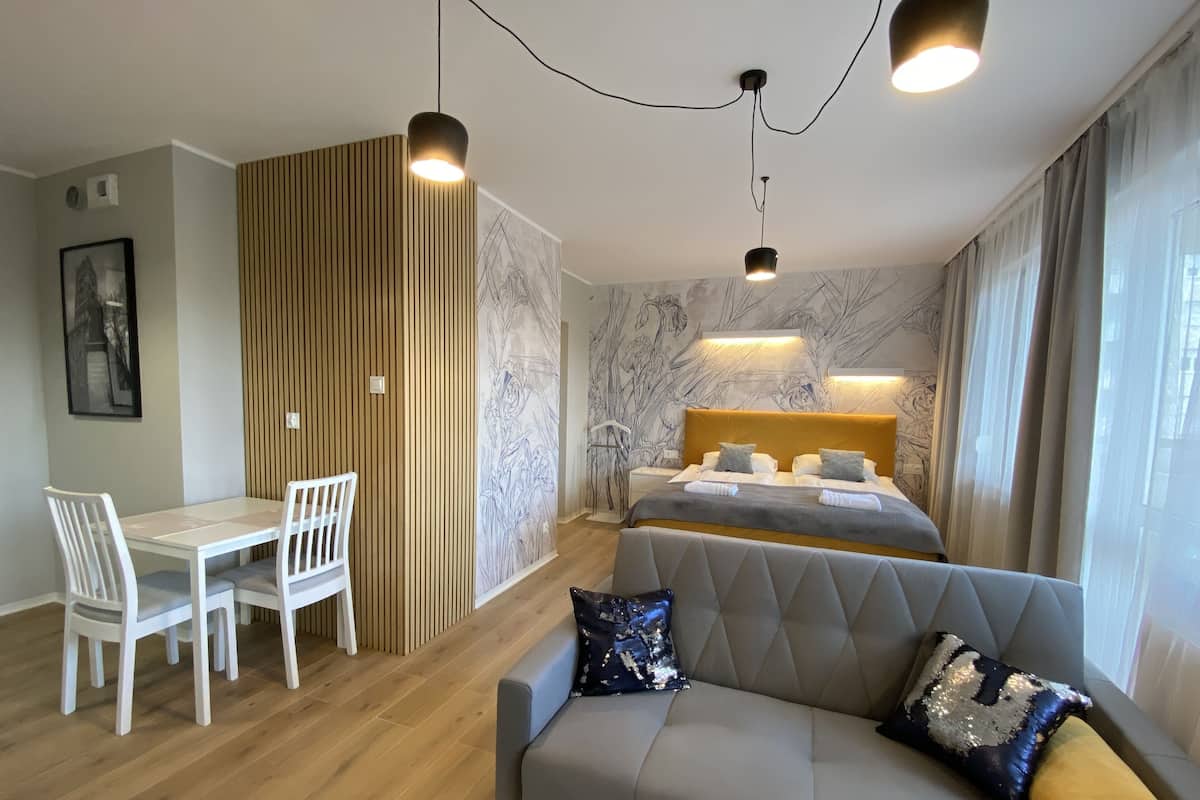 A modern bedroom with a bed, a sofa, a desk, and chairs.