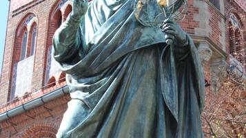 Una estatua de una figura histórica sosteniendo un globo terráqueo, con un edificio al fondo.