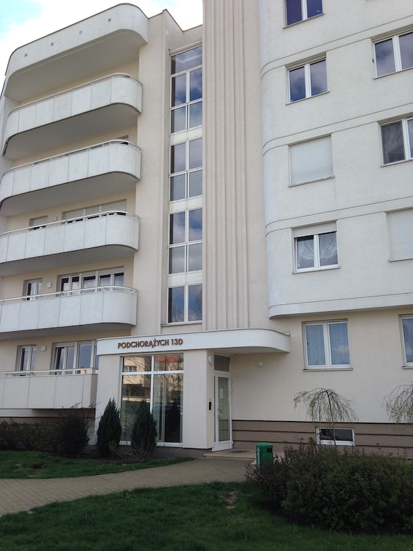 A multi-story building with balconies, a central entrance, and a sign reading "PODCHORAŽYCH 13D". - Apartament Torun (Torun)
