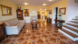 Un salón espacioso con un sofá color beige, una mesa de centro redonda y una escalera que sube a un nivel superior.