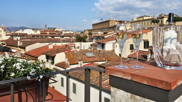 Uma varanda com vista para a paisagem urbana, destacando telhados em terracota e edifícios históricos.