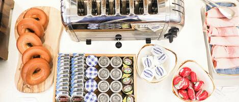 A kitchen counter with a toaster, a tray of donuts, a box of Nutella jars, and a bowl of strawberries.