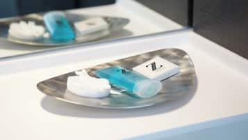 A bathroom vanity with a mirror, a sink, and toiletries including a blue bottle and a white towel.