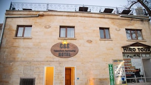 Ein Gebäude mit einer Beschilderung für das CSS Cappadocia Sightseeing Hotel und einem Schild von HIRO TOUR.