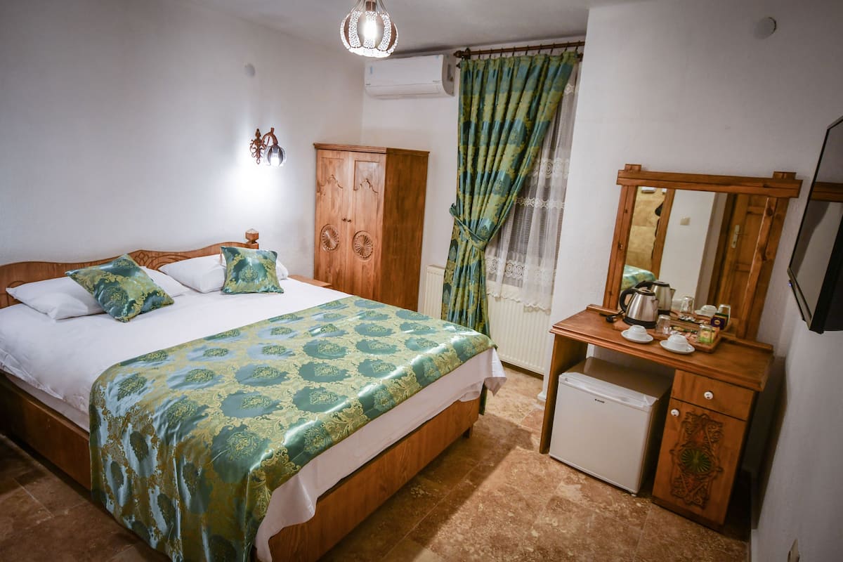 A bedroom with a bed, a wooden dresser, a mirror, and a radiator.