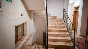 Eine Treppe mit Handlauf, einem Feuerschutzschild und einer Holztür am Ende.