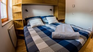 A bedroom with a bed, wooden headboard, and built-in shelving. - Apartments BBI (Luce)