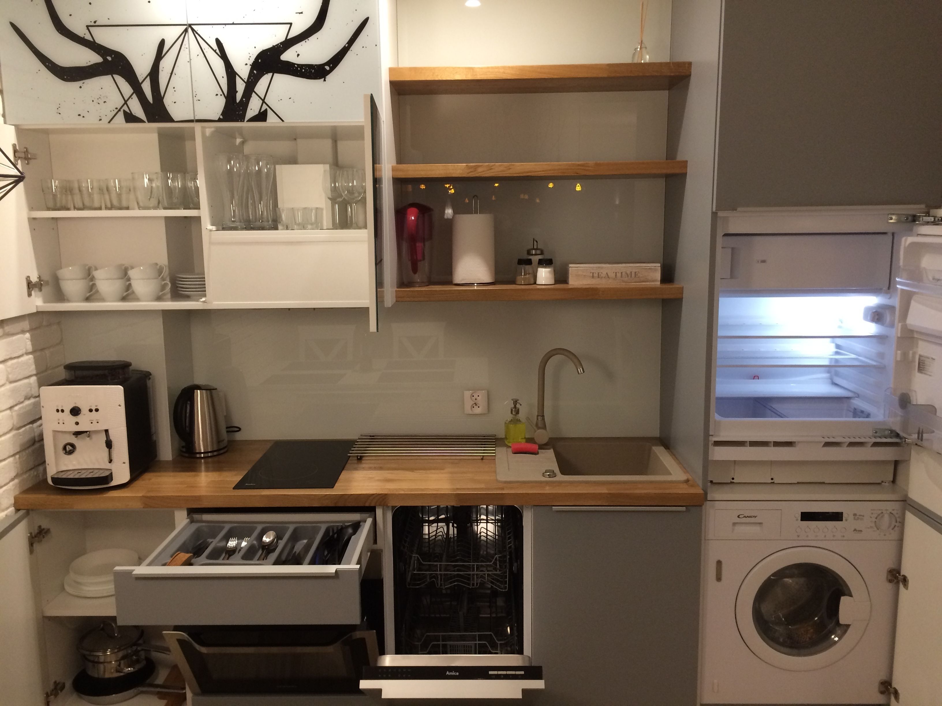 Een compacte keuken met een inbouwvaatwasser, een koffieapparaat en een wasmachine.