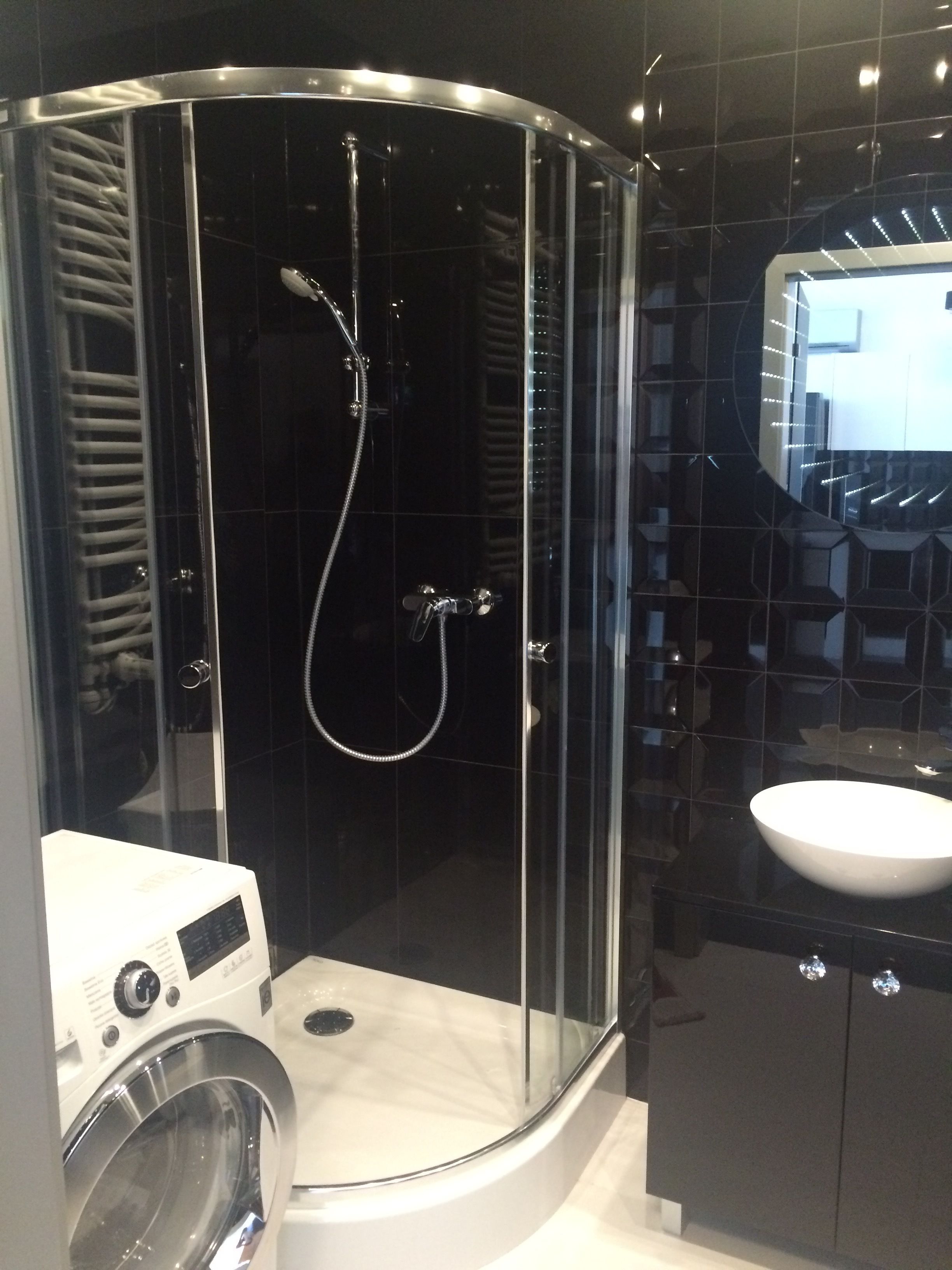 A modern bathroom with a glass-enclosed shower, a white sink, and a built-in washing machine.