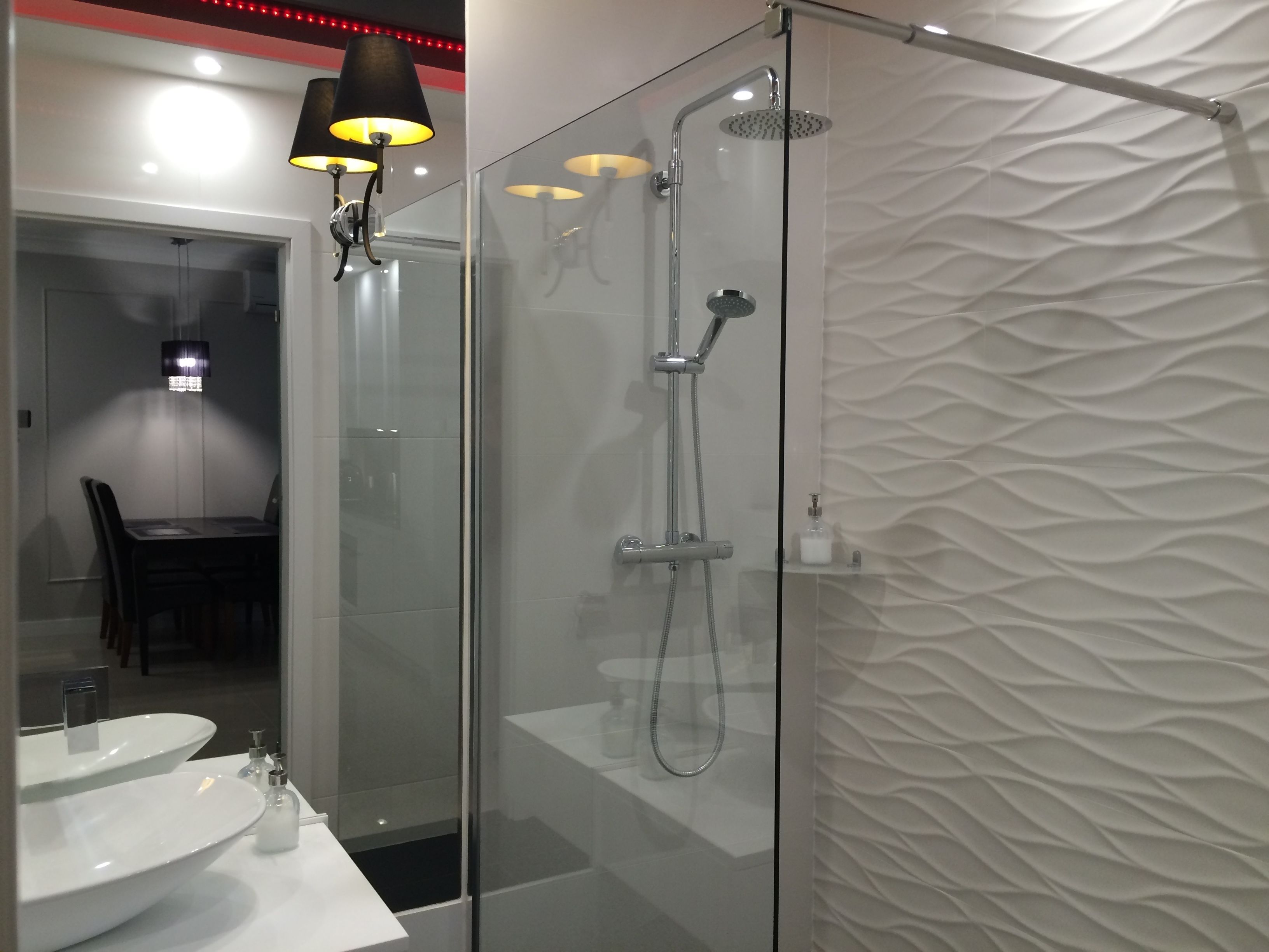A modern bathroom with a glass-enclosed shower, a white sink, and a table with chairs.