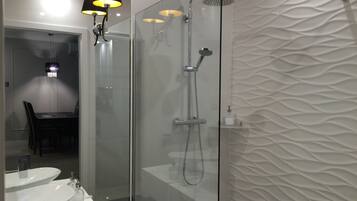 A modern bathroom with a glass-enclosed shower, a white sink, and a table with chairs.