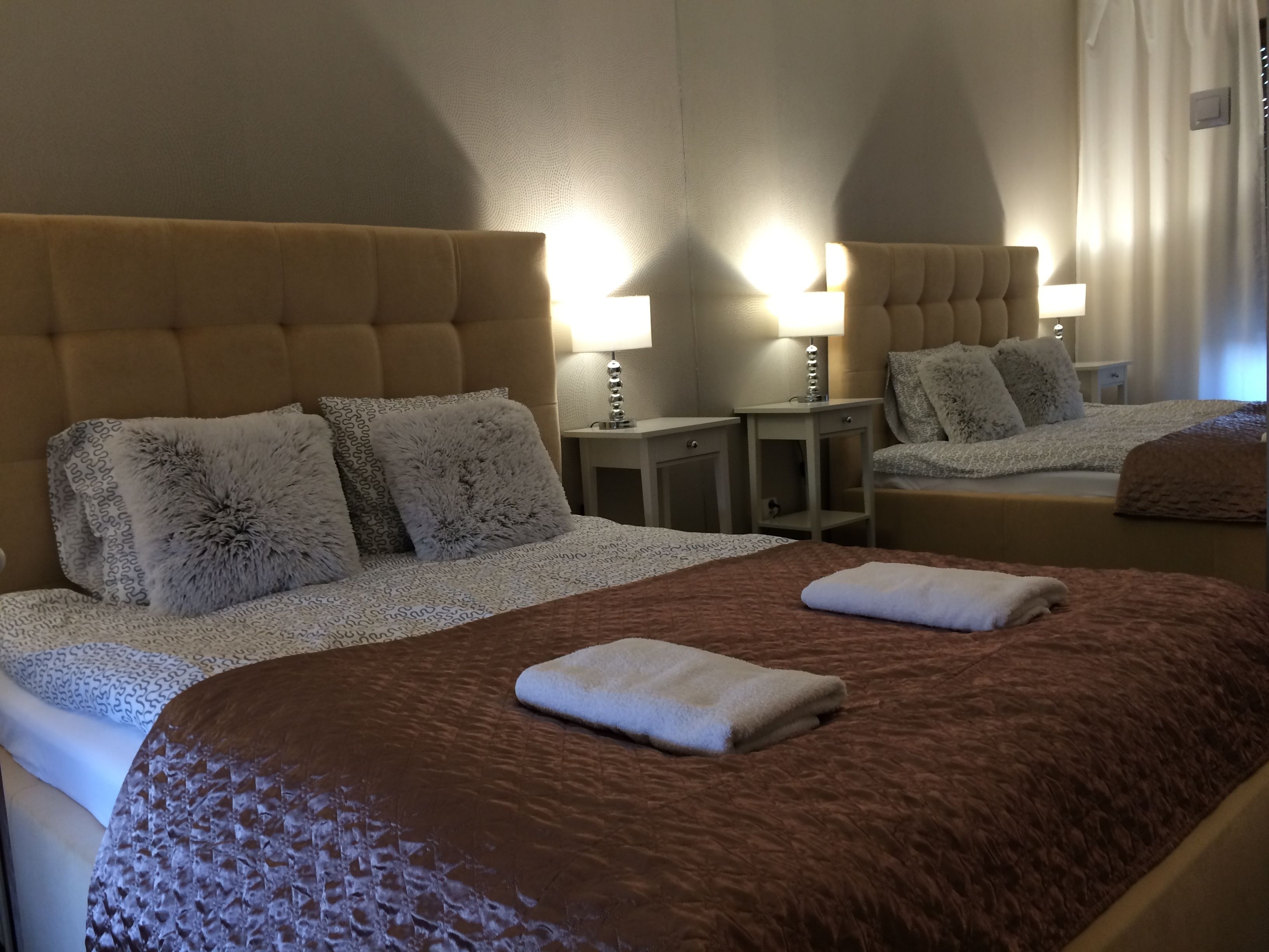 A hotel room with a large bed, two bedside tables with lamps, and a headboard.