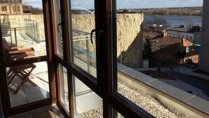 Habitació amb finestres grans que donen a una vista panoràmica de la ciutat, incloent un pont i edificis.