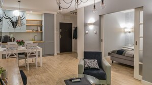 Un espai de vida modern amb zona de menjador, taula de cafè de vidre, sofà i cuina al fons.