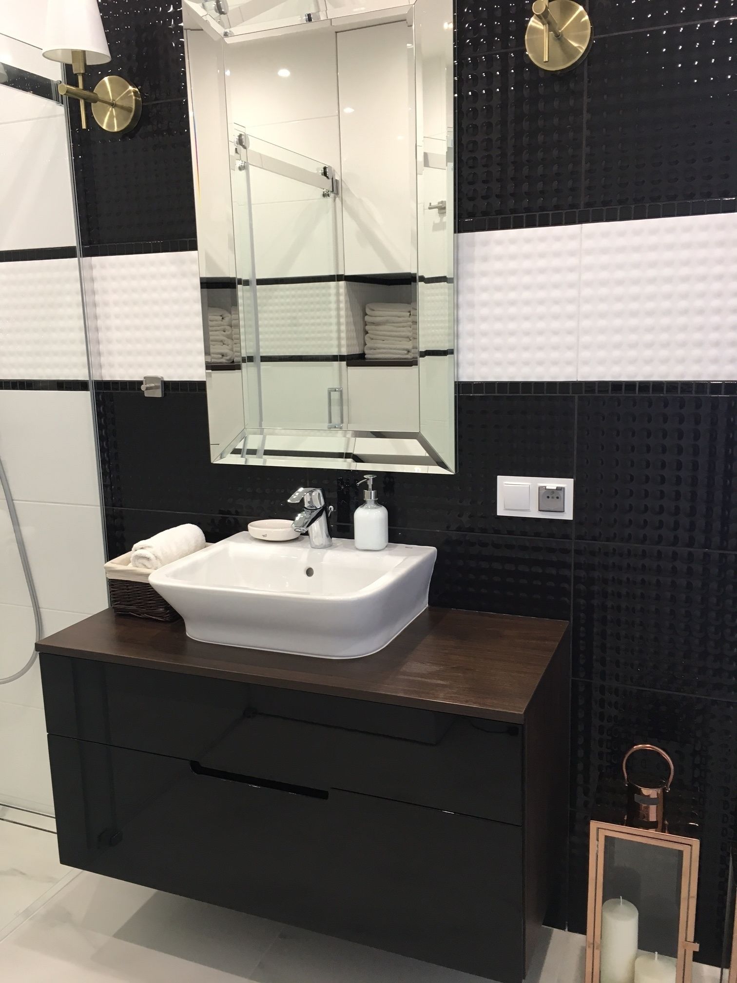 A modern bathroom with a white sink, dark wooden vanity, and a large mirror.