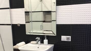 A modern bathroom with a white sink, dark wooden vanity, and a large mirror.