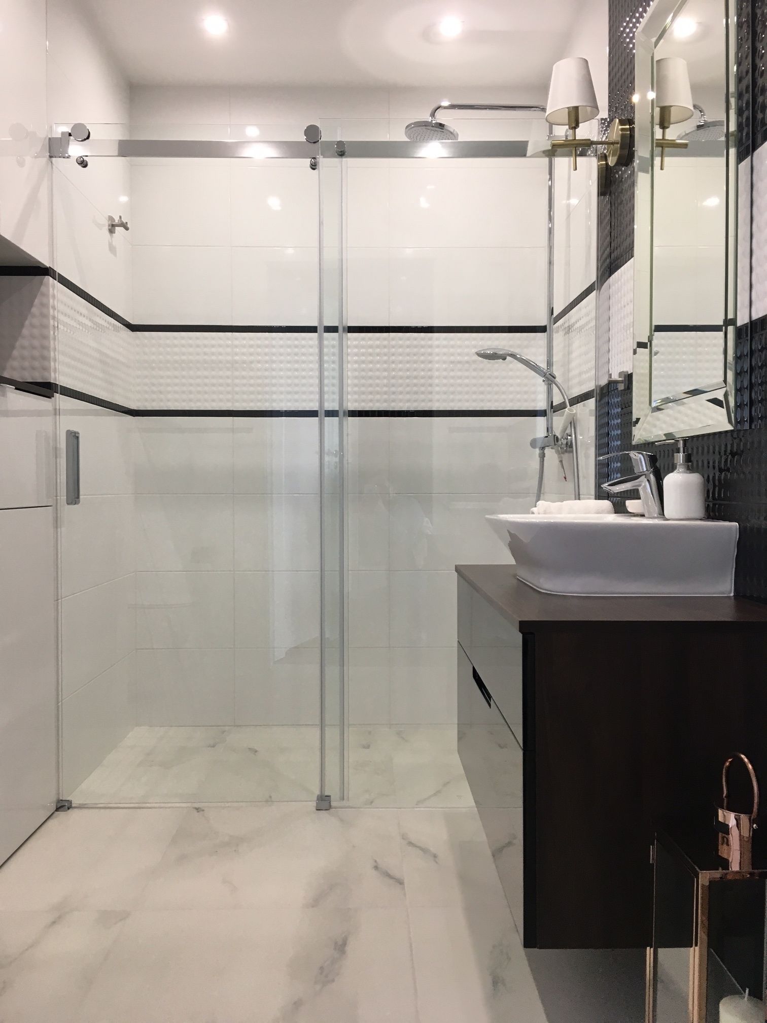A modern bathroom with a glass-enclosed shower, a white sink, and a dark vanity.