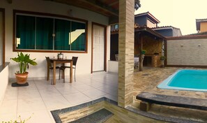 Um pátio com uma mesa de jantar e cadeiras, um vaso de planta e uma piscina.