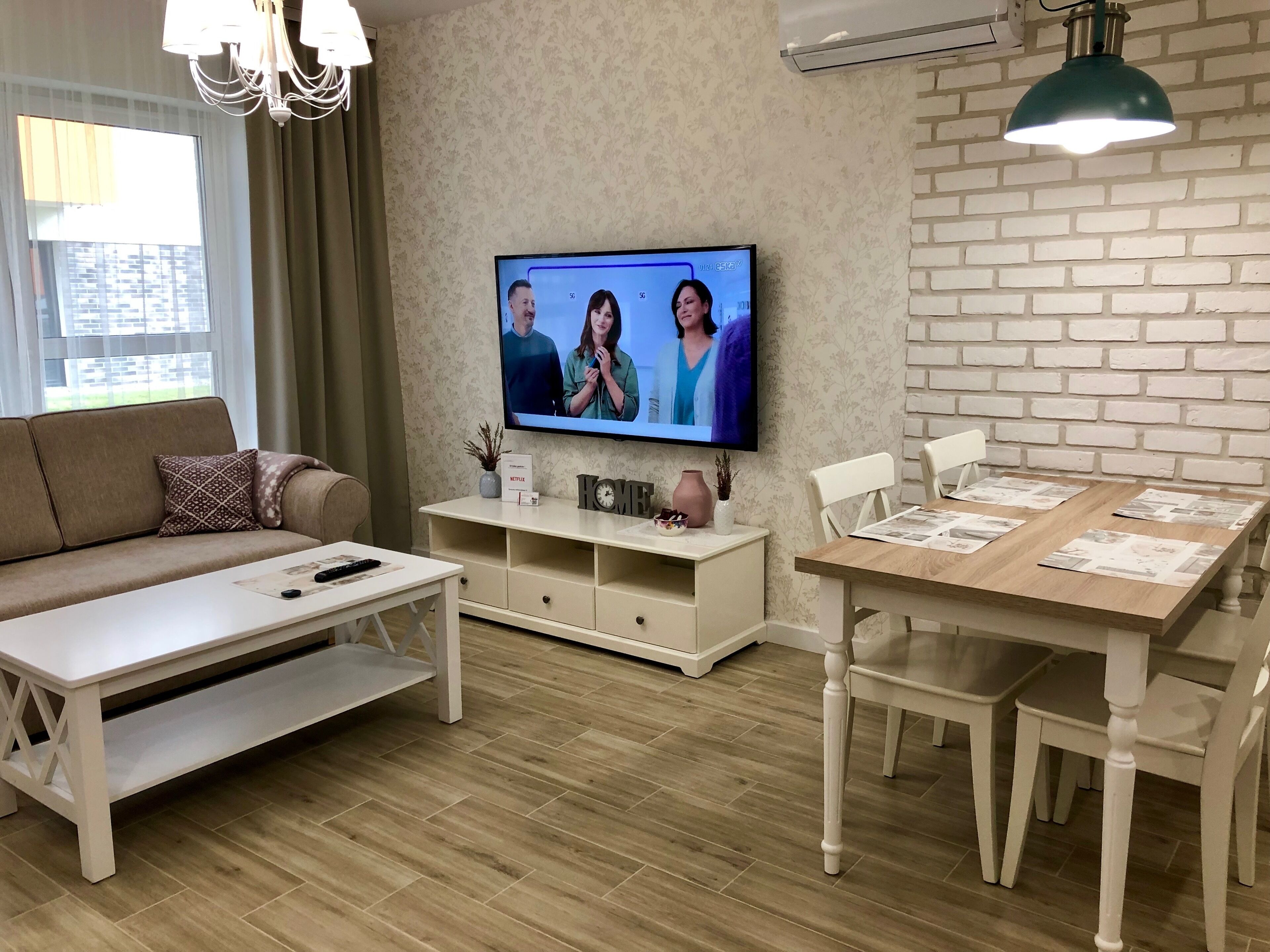 A modern living room with a sofa, coffee table, TV, and dining area.