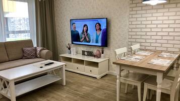 A modern living room with a sofa, coffee table, TV, and dining area.