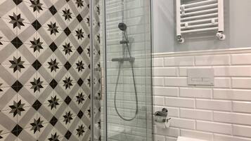 A bathroom with a shower, toilet, and a towel rack.