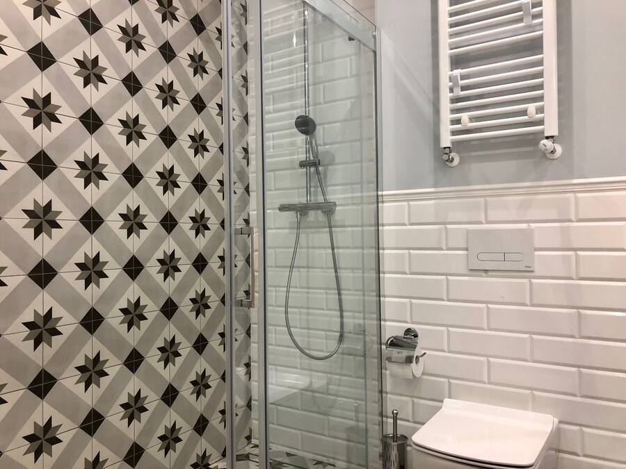 A bathroom with a shower, toilet, and a towel rack.
